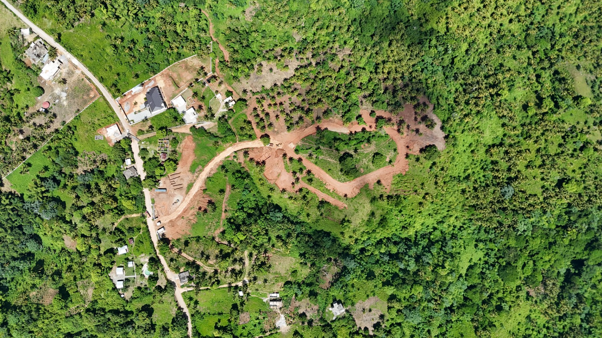 Aerial photograph of red earth roads cut through green hillside vegetation at Nomad City