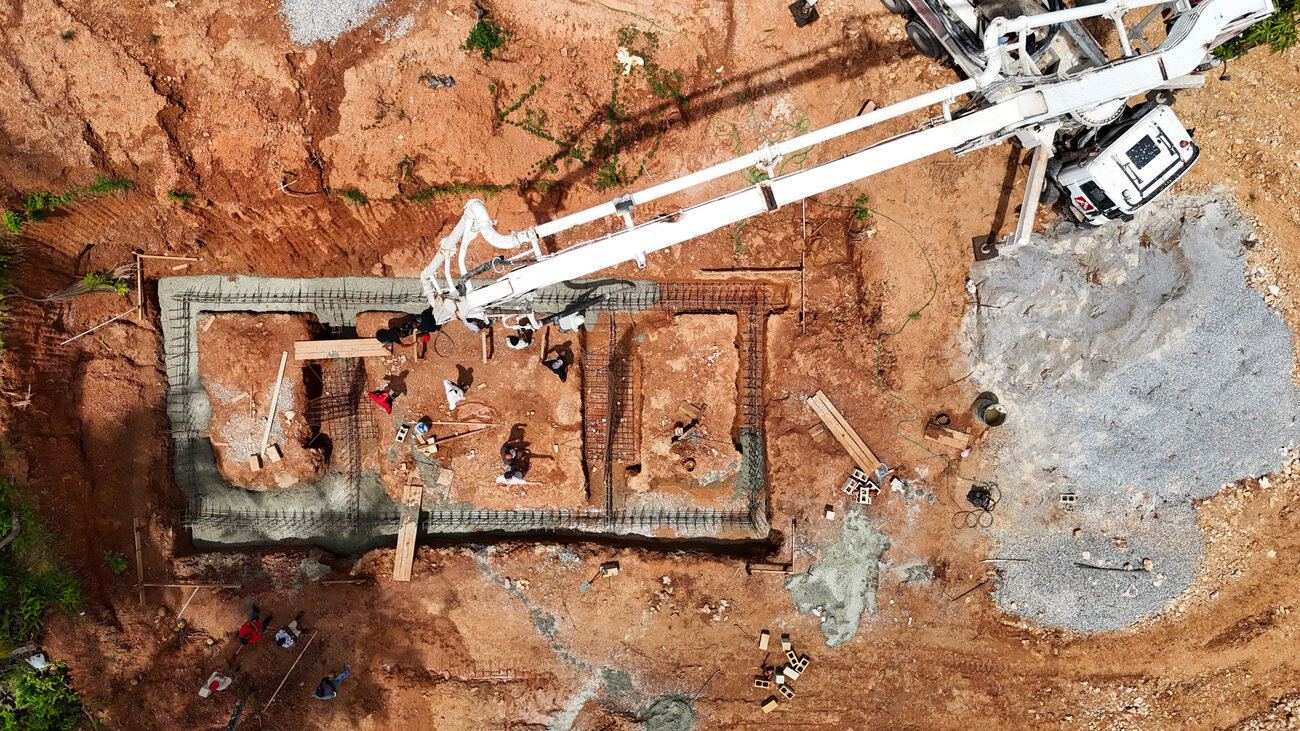 Aerial view looking straight down on a concrete pump placing a house foundation