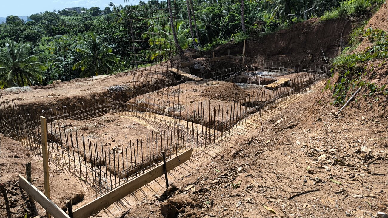 Wide view of a house foundation with formwork and reinforcement in place on cut ground