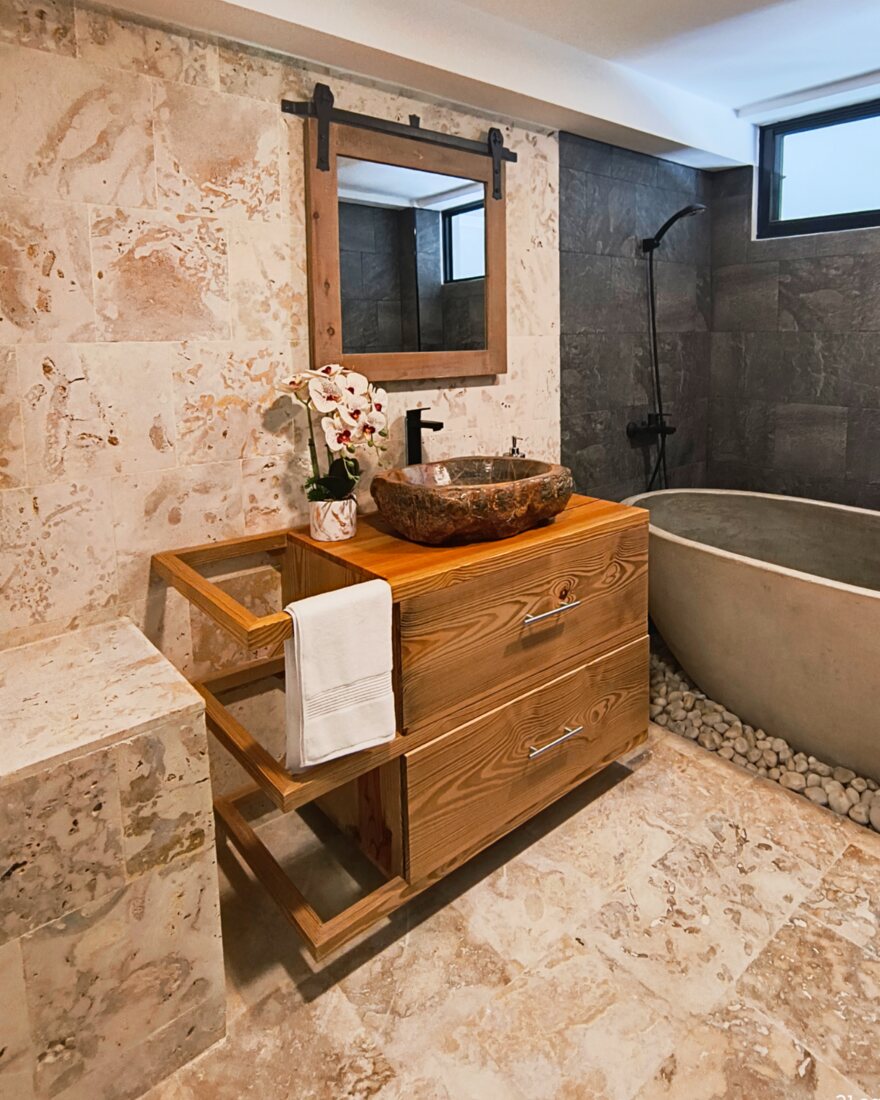 Showroom bathroom clad in coralina stone with a timber vanity and a tub