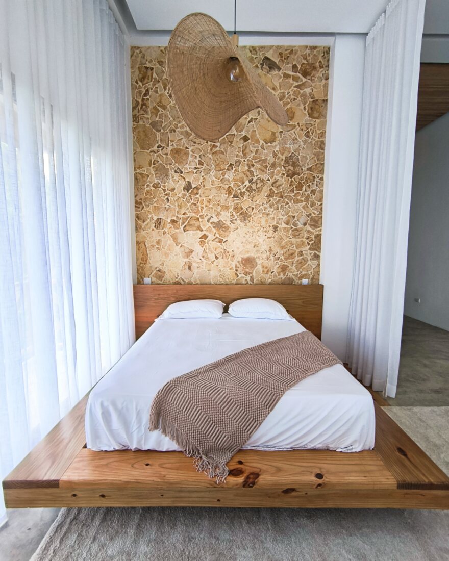 Showroom bedroom with a coralina stone feature wall and a timber platform bed