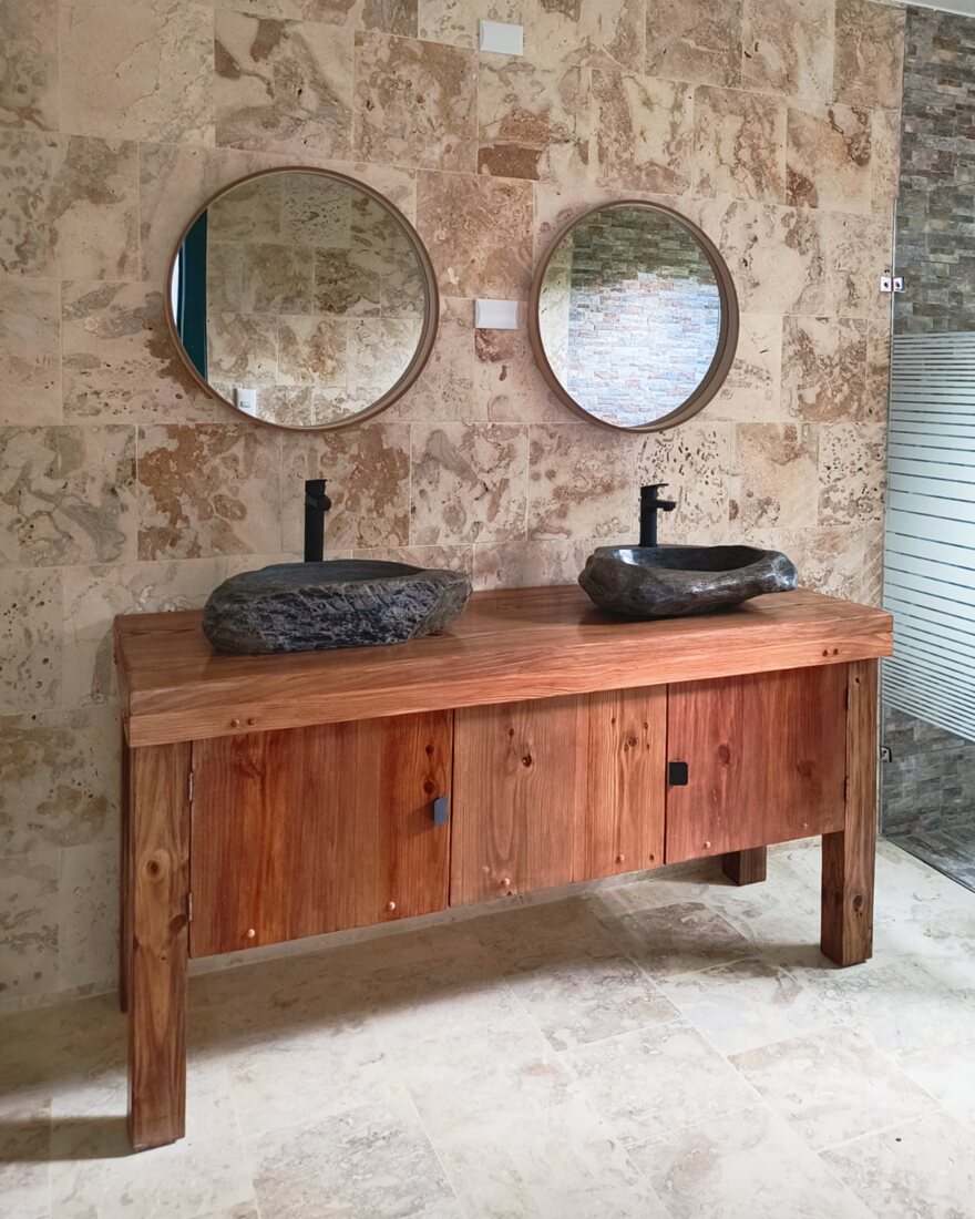 Showroom bathroom vanity in hardwood with two carved stone basins and round mirrors