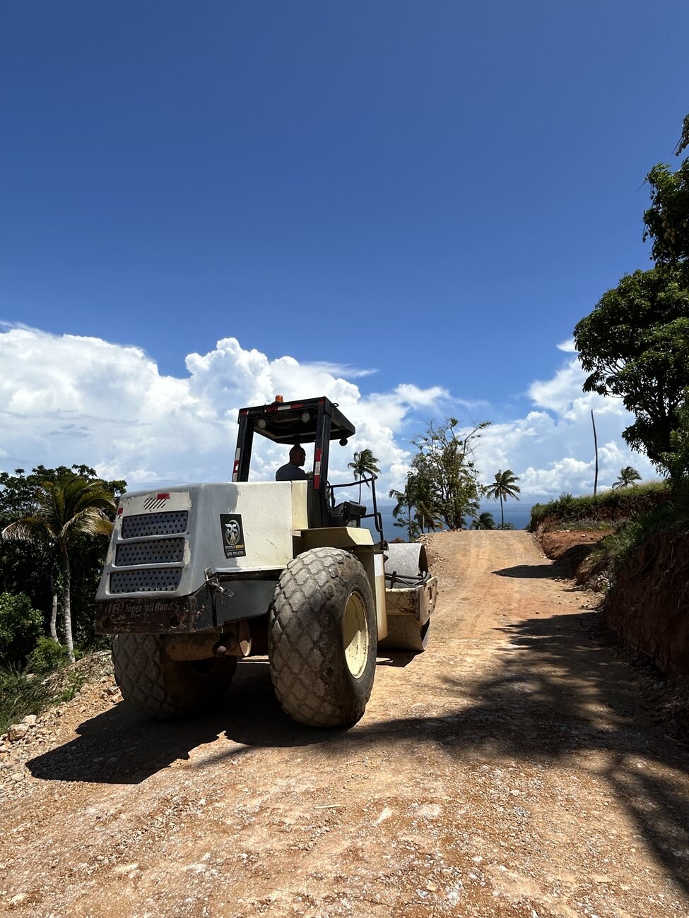 A roller compacting the surface of a road running along the ridge towards the sea