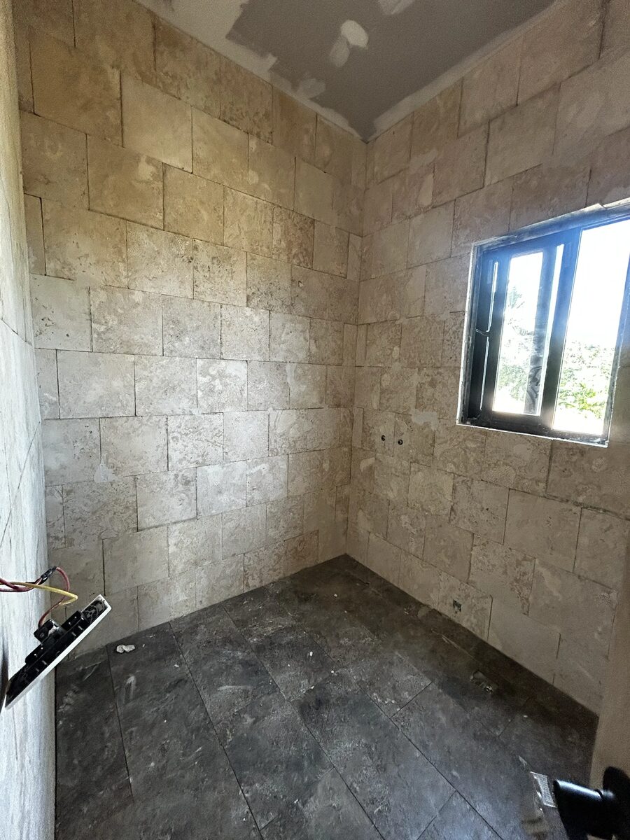 A bathroom with stone-clad walls and dark tiled floor