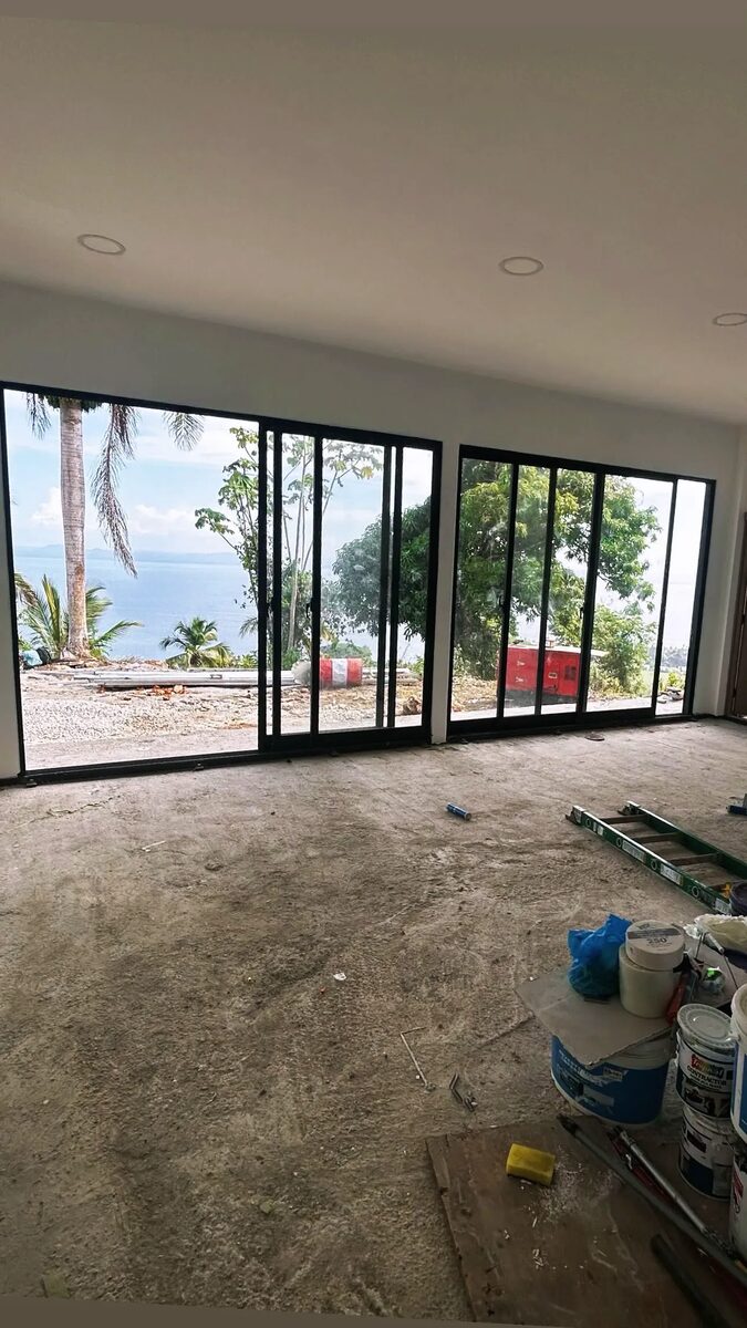 Interior with full-height sliding glass doors open to palm trees and the sea