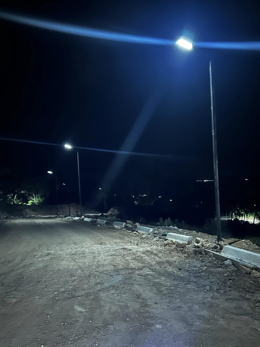 A newly built road at night lit by installed street lights, kerbs in place
