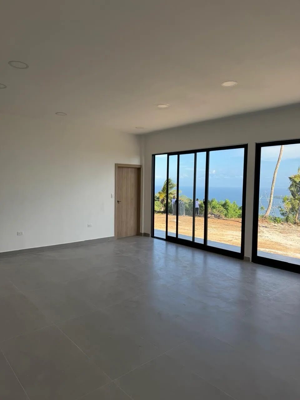 An interior room with a wooden door and full-height sliding doors framing the open sea