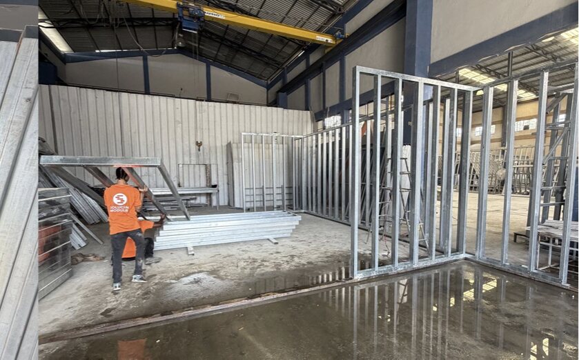 Galvanised steel wall frames standing assembled on the plant floor beside stacked profiles