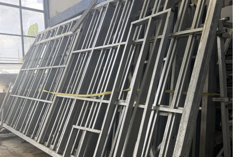 A long run of fabricated galvanised steel wall panels stored upright in the plant