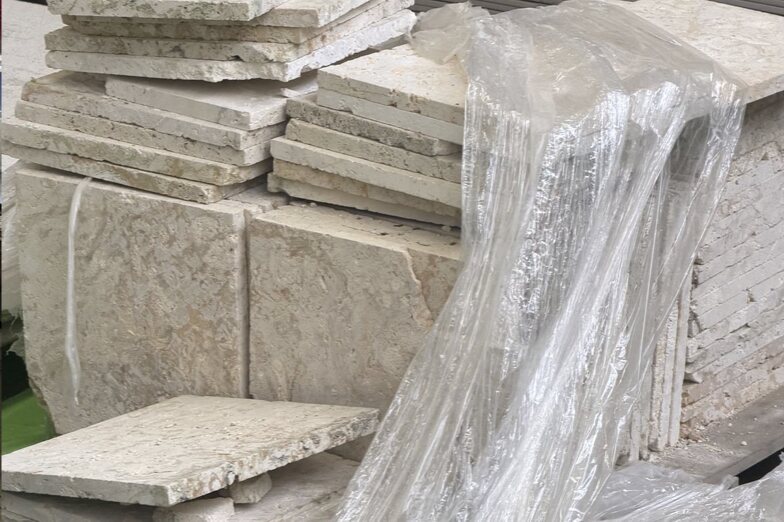 Stacked natural stone slabs and tiles wrapped on pallets in plant storage
