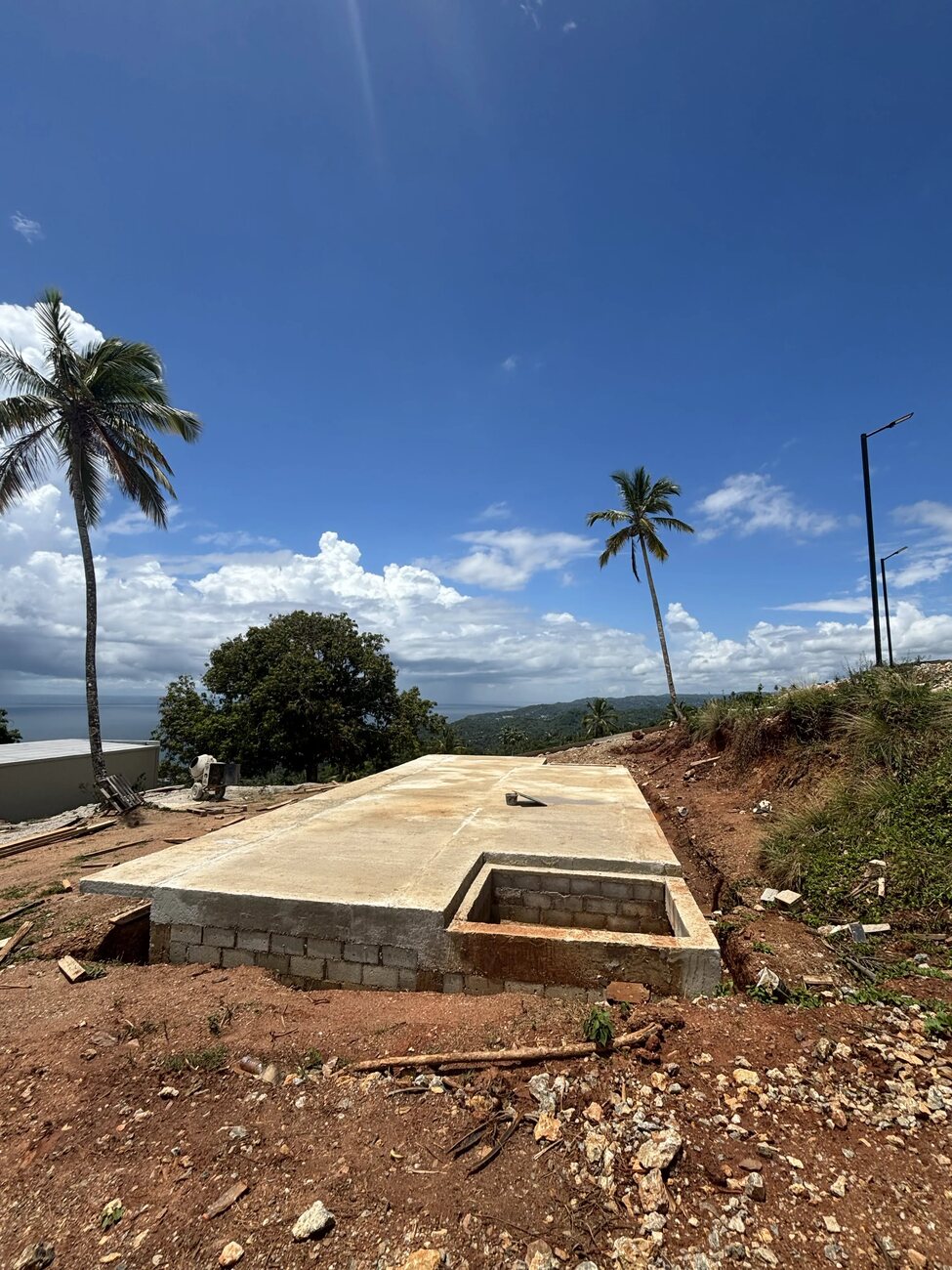A concrete slab raised on a block plinth on a levelled terrace, solar street lights standing behind