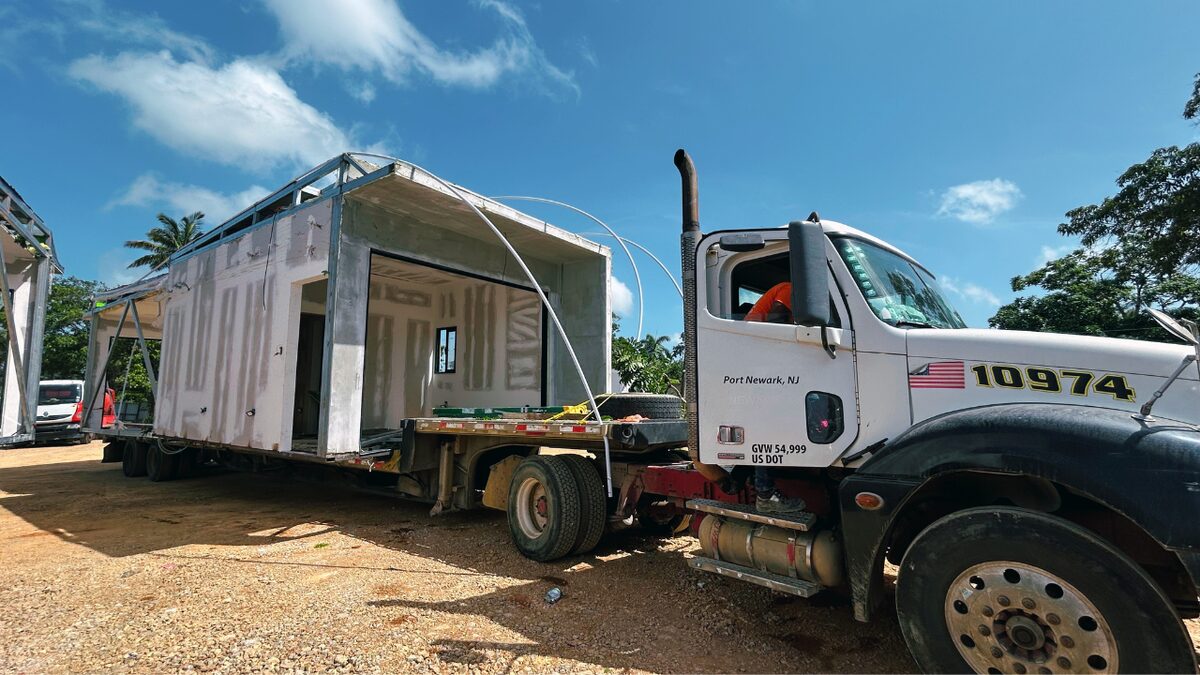A modular house module arriving on a flatbed truck at the Nomad City site